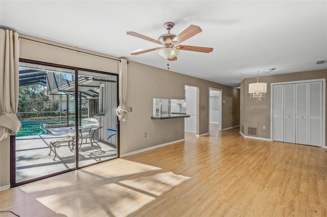 interior space featuring ceiling fan with notable chandelier and light wood-type flooring