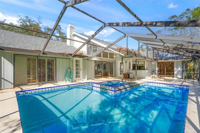 view of swimming pool featuring glass enclosure, an in ground hot tub, and a patio