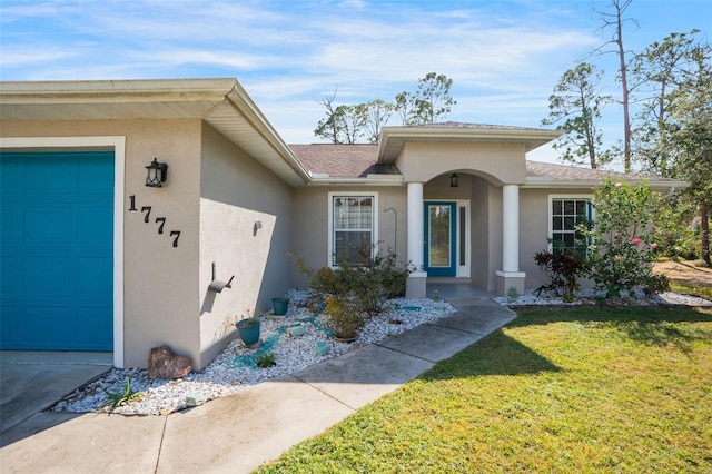 doorway to property with a garage and a lawn