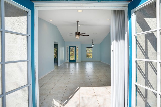 interior space with vaulted ceiling, light tile patterned floors, and ceiling fan