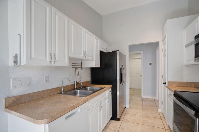 kitchen with white cabinets, stainless steel appliances, sink, and light tile patterned floors