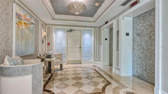 foyer featuring a tray ceiling, elevator, a notable chandelier, and ornamental molding