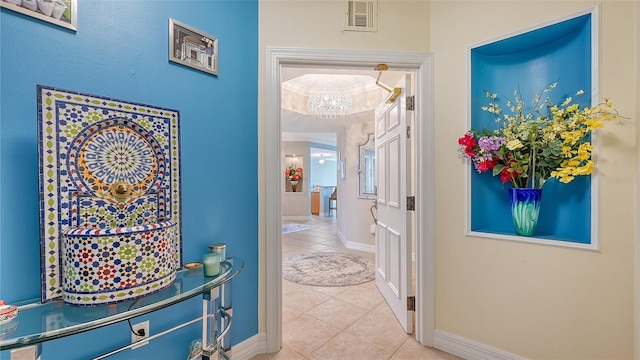 corridor featuring tile patterned flooring, an inviting chandelier, and ornamental molding