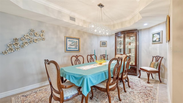 dining room featuring a tray ceiling, an inviting chandelier, and ornamental molding