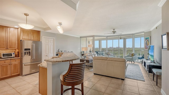 kitchen with hanging light fixtures, a breakfast bar area, light tile patterned floors, and high end fridge