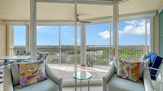 sunroom with ceiling fan, plenty of natural light, and a water view