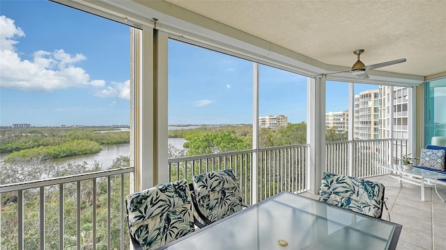 sunroom featuring ceiling fan and a water view