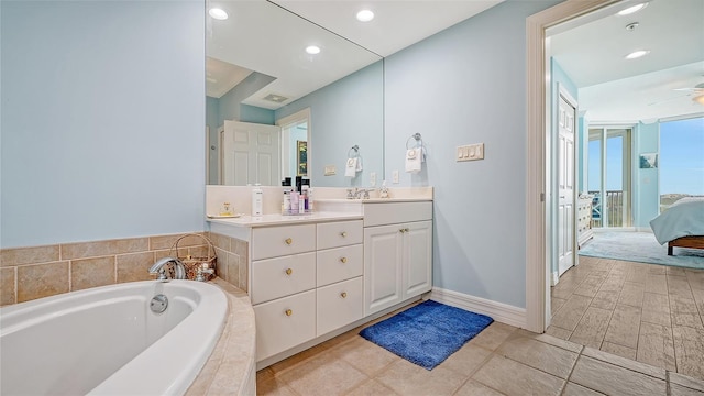 bathroom with tiled bath, ceiling fan, and vanity