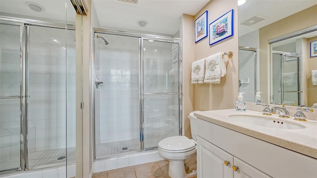 bathroom with tile patterned flooring, vanity, toilet, and a shower with door