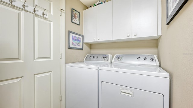 clothes washing area featuring cabinets and independent washer and dryer