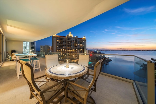 balcony at dusk featuring a water view