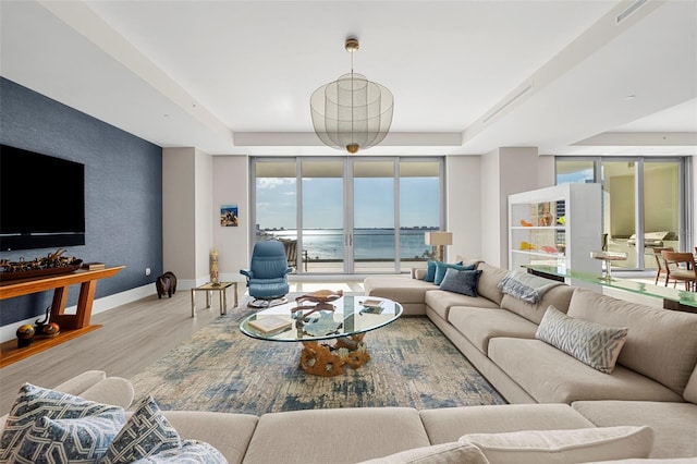 living room featuring expansive windows, a water view, and light wood-type flooring