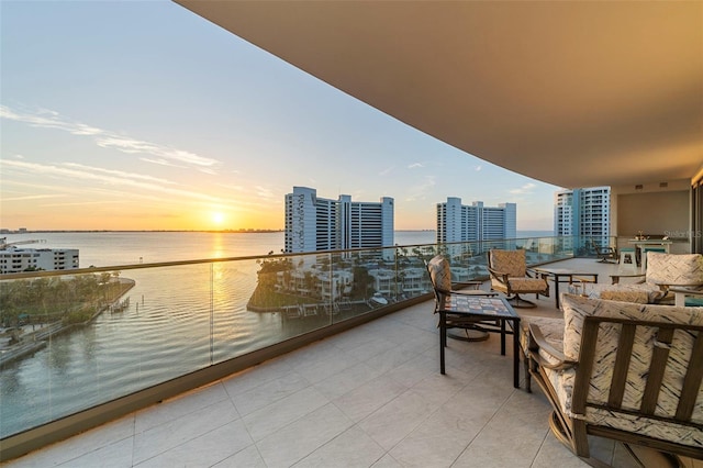 balcony at dusk featuring a water view