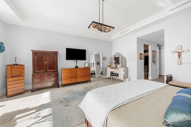 bedroom with a spacious closet, light hardwood / wood-style floors, and a closet