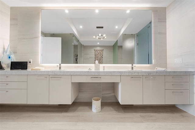 bathroom featuring vanity, a tray ceiling, and tile walls