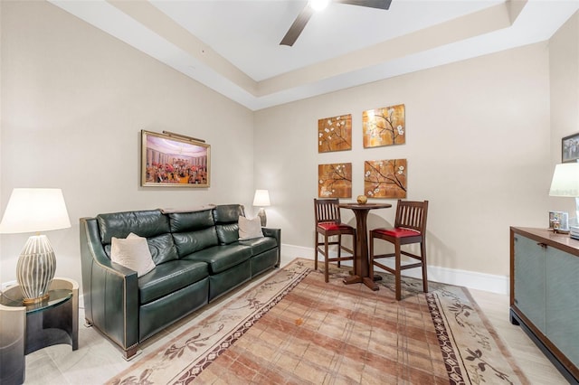 living room featuring ceiling fan and a raised ceiling