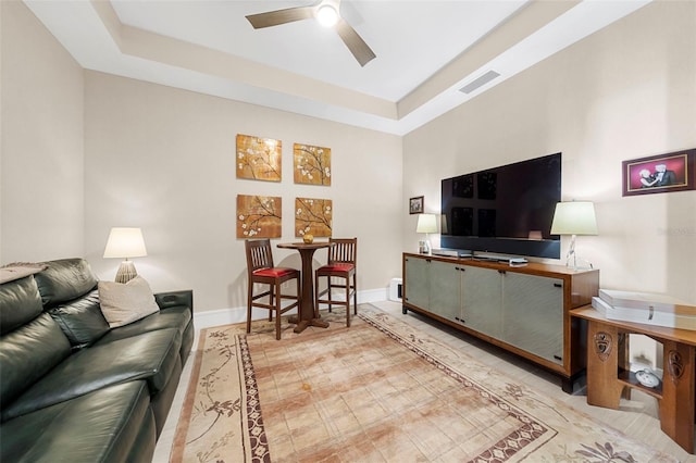 living room with a tray ceiling, a towering ceiling, and ceiling fan