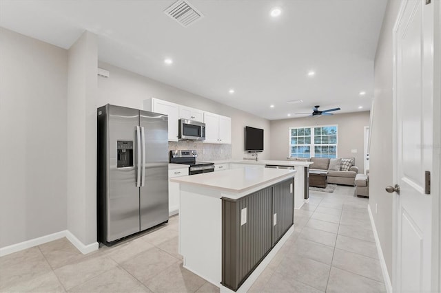 kitchen with stainless steel appliances, light tile patterned flooring, and white cabinetry