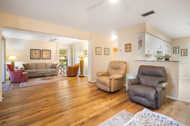 living room featuring light hardwood / wood-style floors and ceiling fan