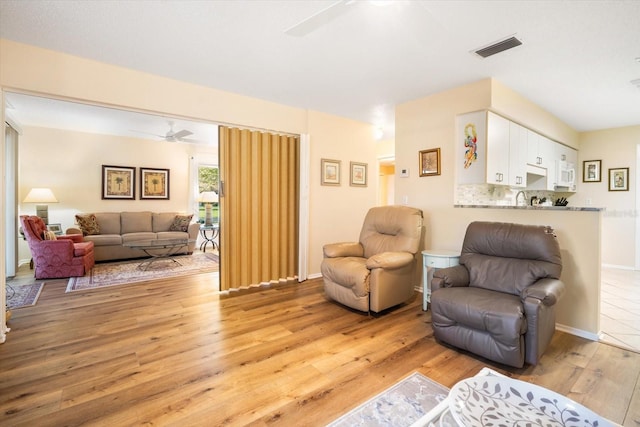 living room featuring light wood-type flooring and ceiling fan