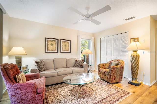 living room featuring a textured ceiling, wood-type flooring, and ceiling fan