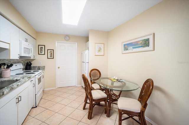 kitchen featuring white appliances, backsplash, light tile patterned floors, and white cabinets