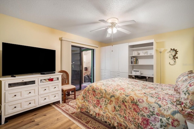 bedroom featuring ceiling fan, hardwood / wood-style flooring, access to outside, and a textured ceiling