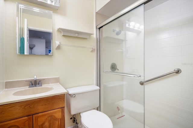 bathroom featuring toilet, a shower with shower door, and vanity