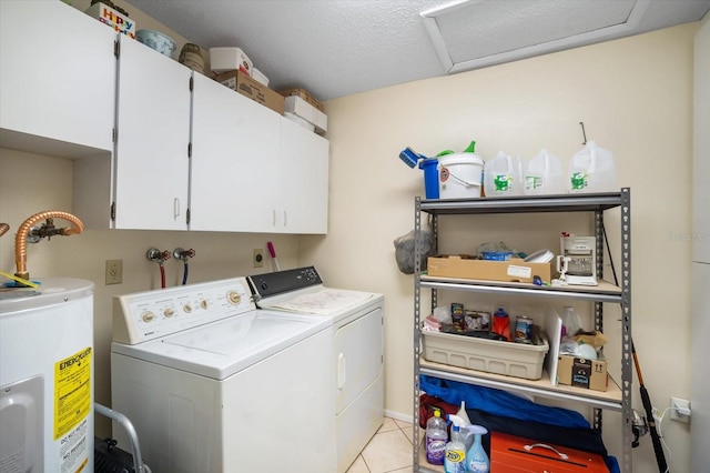 laundry room featuring water heater, light tile patterned floors, washer and dryer, a textured ceiling, and cabinets