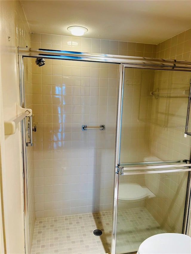 bathroom with toilet and a shower with shower door