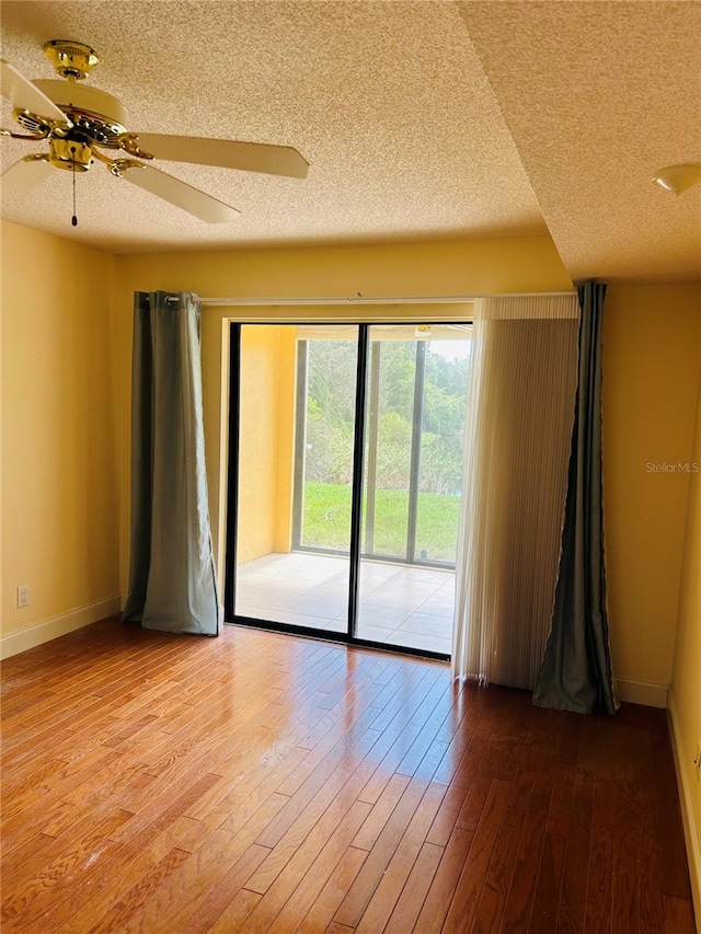 unfurnished room featuring ceiling fan, wood-type flooring, and a textured ceiling