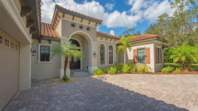 exterior space featuring a garage, a tile roof, and stucco siding