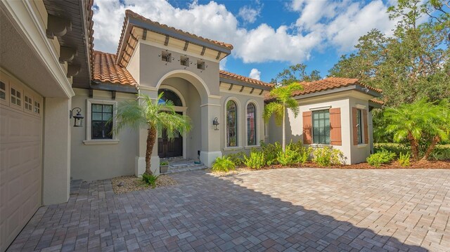 9291 Swaying Branch Rd, Sarasota, FL 34241 - entrance to property with stucco siding, a tiled roof, and a garage