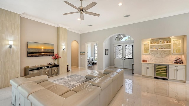 living area with arched walkways, a dry bar, visible vents, ornamental molding, and beverage cooler