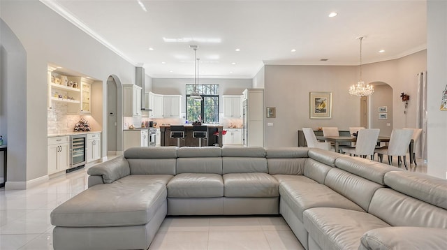 living room with wine cooler, crown molding, light tile patterned floors, and a chandelier