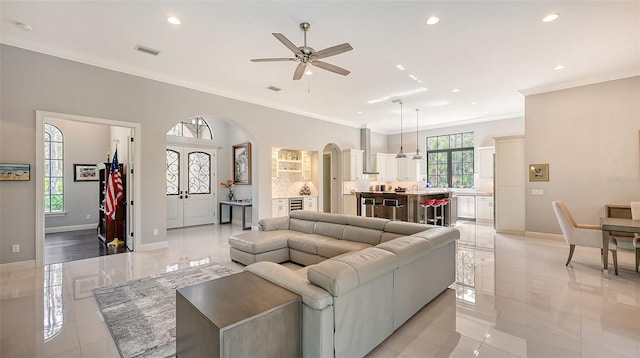 living area with baseboards, visible vents, arched walkways, crown molding, and recessed lighting