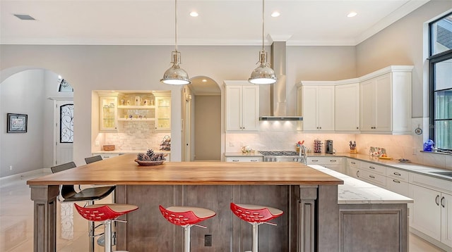 9291 Swaying Branch Rd, Sarasota, FL 34241 - kitchen with arched walkways, a spacious island, wood counters, backsplash, and crown molding