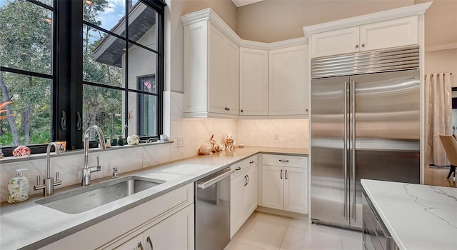 9291 Swaying Branch Rd, Sarasota, FL 34241 - kitchen featuring appliances with stainless steel finishes, a sink, tasteful backsplash, and white cabinetry