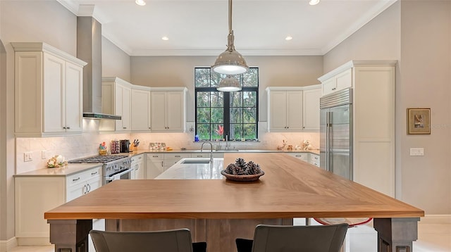 kitchen with premium appliances, a kitchen island with sink, a sink, light countertops, and a kitchen bar