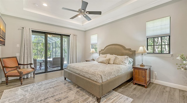 bedroom with ornamental molding, a tray ceiling, access to outside, light hardwood / wood-style floors, and ceiling fan