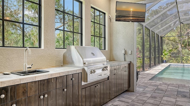 view of patio / terrace with an outdoor pool, area for grilling, glass enclosure, grilling area, and a sink