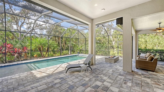 view of pool featuring an outdoor living space with a fire pit, ceiling fan, a patio, and a lanai