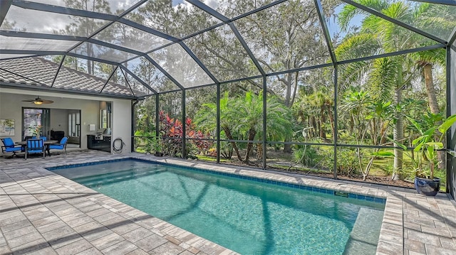 view of swimming pool featuring ceiling fan, a patio, and a lanai