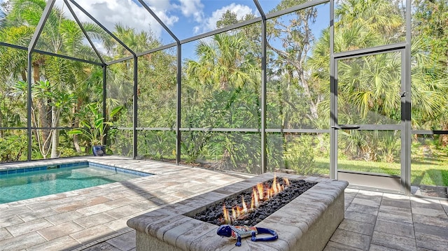 outdoor pool featuring glass enclosure, a fire pit, and a patio