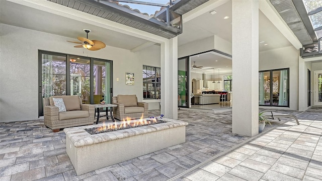 view of patio with ceiling fan and an outdoor living space with a fire pit