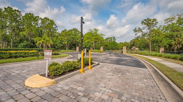 view of street featuring a gate, curbs, a gated entry, and street lights