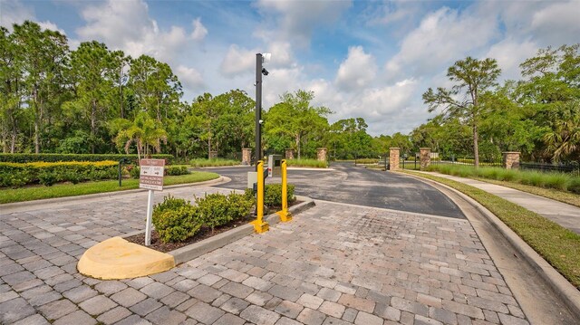 9291 Swaying Branch Rd, Sarasota, FL 34241 - view of road with street lights, curbs, a gated entry, sidewalks, and view of wooded area