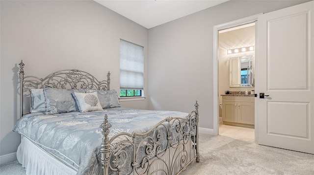 bedroom with light colored carpet, connected bathroom, and baseboards