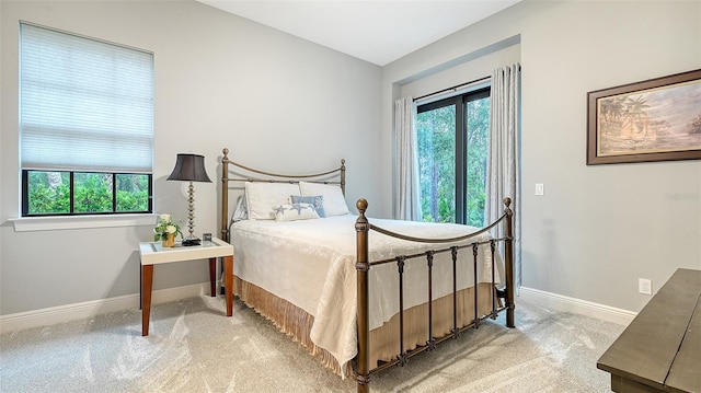 bedroom with light carpet, multiple windows, and baseboards