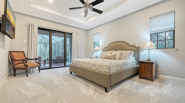 carpeted bedroom with baseboards, a raised ceiling, ornamental molding, access to exterior, and multiple windows